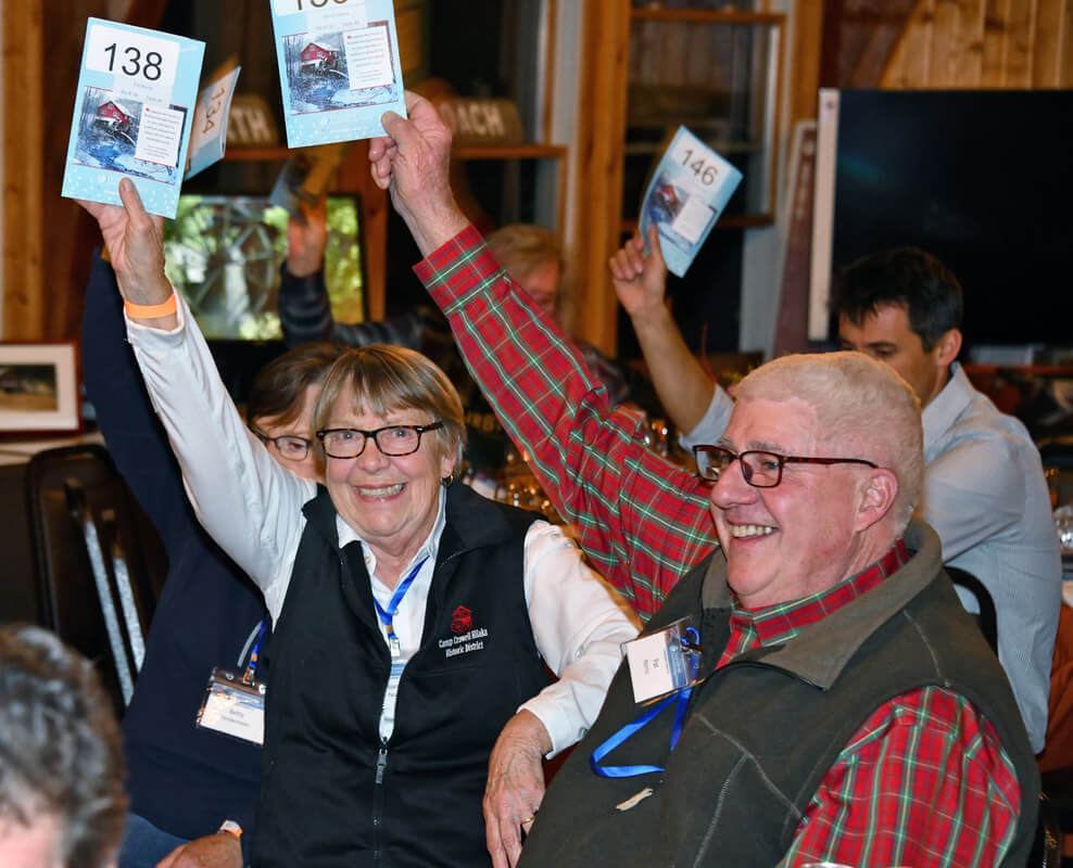 attendees raise their bid placards at an auction